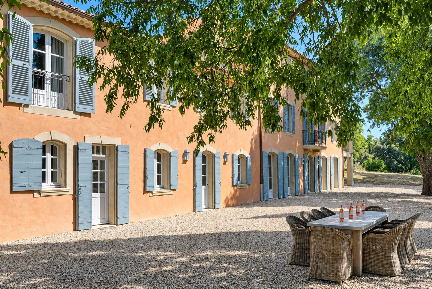 Bastide aux volets bleus et sa cour de gravier ombragée