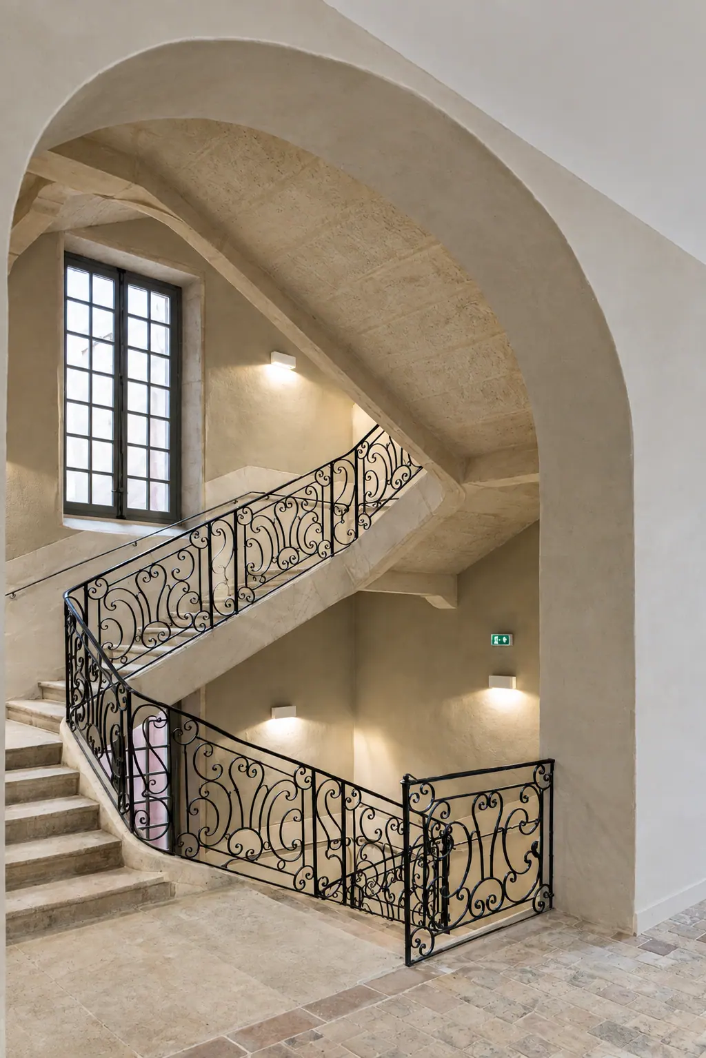 Escalier de pierre à rampe en fer forgé, éclairé par une haute fenêtre bois à petits-bois, Mâcon (2021)