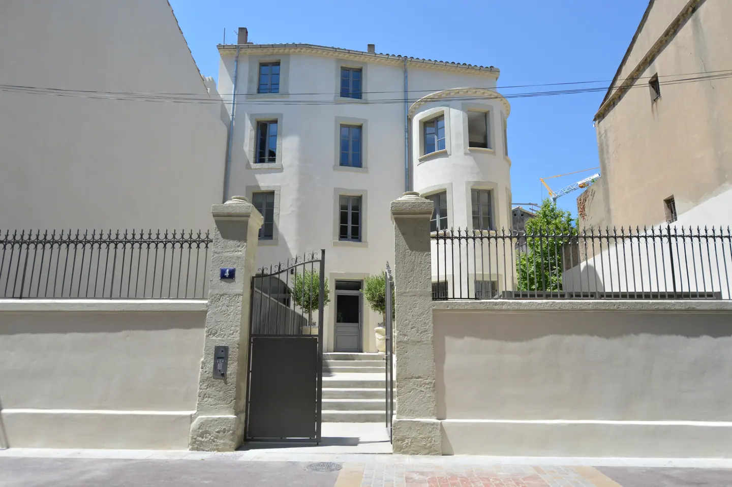 Immeuble du 8 place Thérèse-et-Léon-Blum à Narbonne derrière sa grille, menuiseries bois en façade