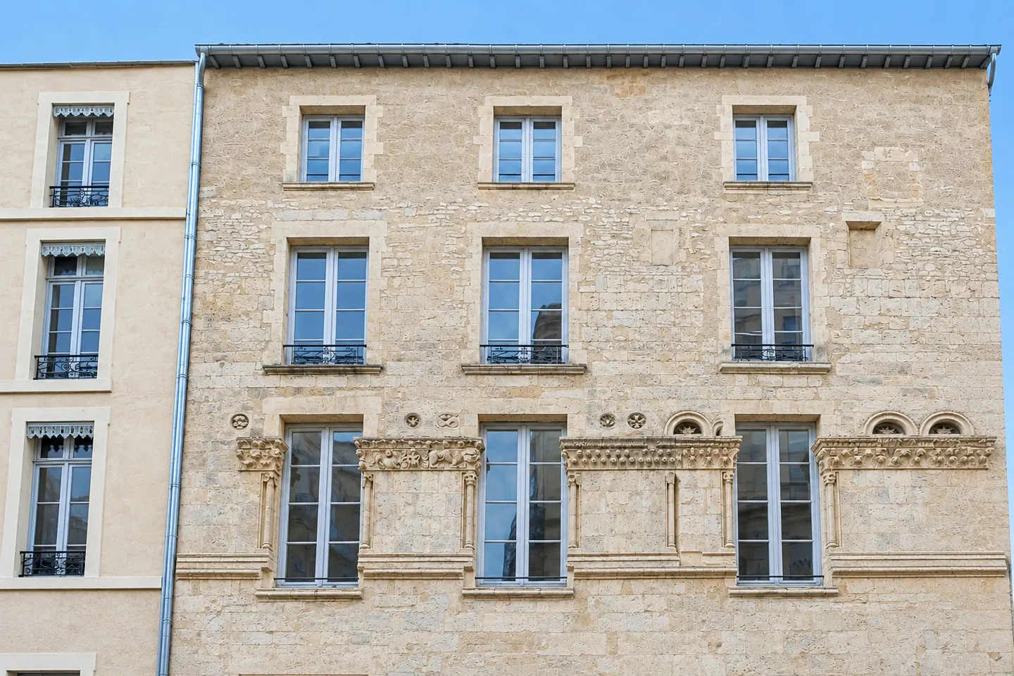 Façade de pierre sculptée du 1 rue de la Madeleine à Nîmes et ses menuiseries bois