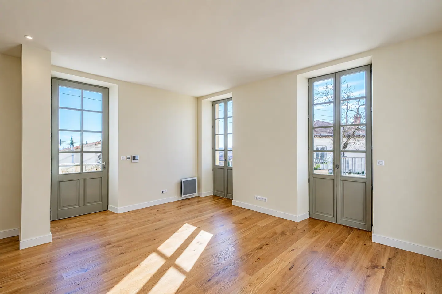 Pièce au parquet de chêne baignée de soleil, portes-fenêtres bois laquées gris, 9 rue de la Poudrière à Nîmes