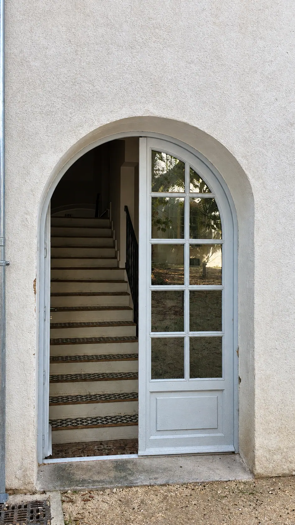 Porte vitrée cintrée à petits-bois ouvrant sur un escalier
