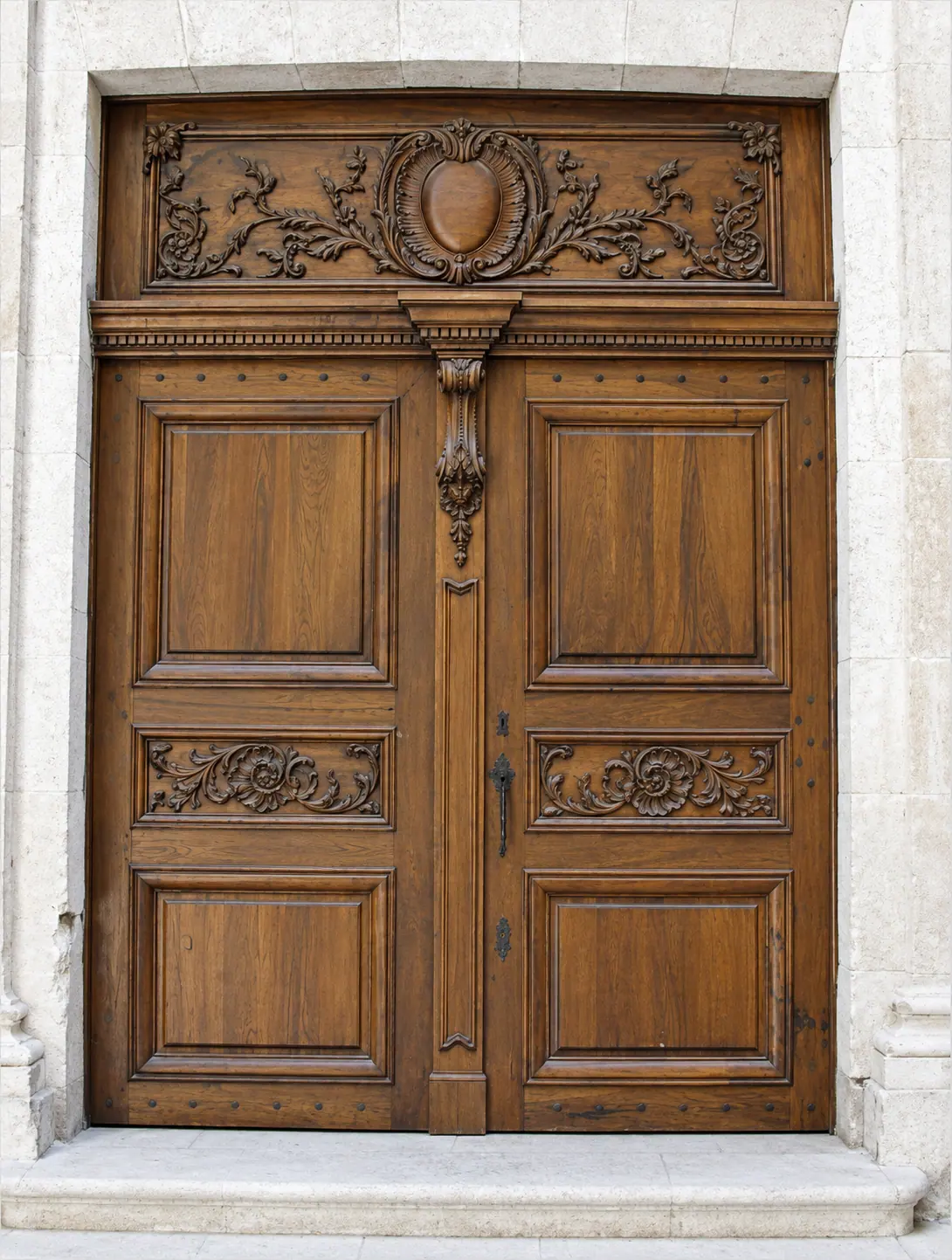 Porte d'entrée à deux vantaux en chêne sculpté dans un encadrement de pierre