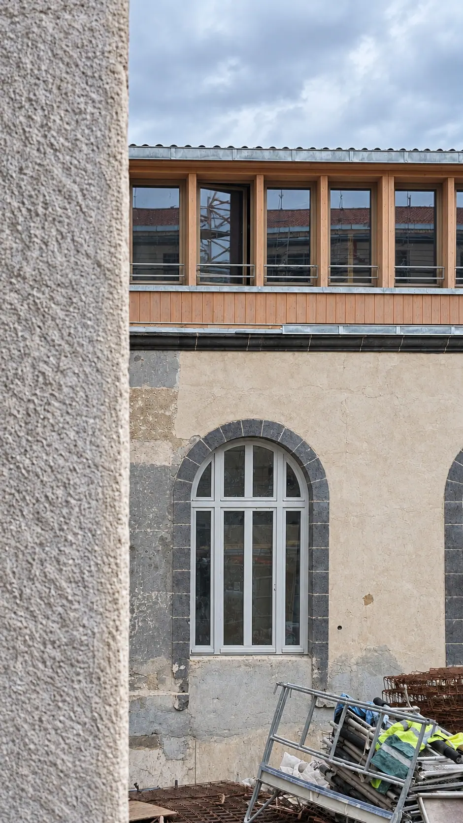 Fenêtre cintrée neuve dans un mur de basalte, chantier en cours