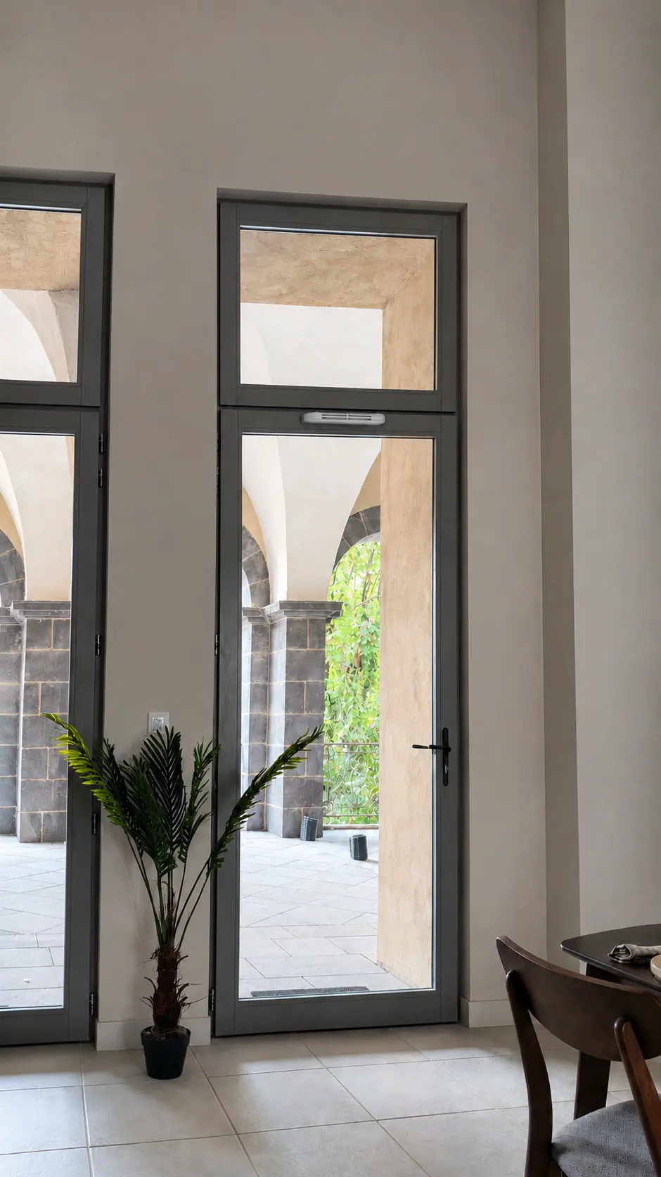 Portes-fenêtres bois sombres ouvrant sur une galerie à arcades