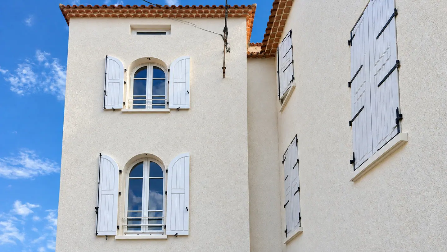 Façade blanche aux fenêtres cintrées et volets ouverts, villa du Trayas à Saint-Raphaël