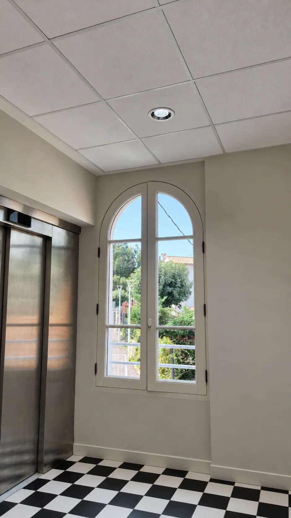 Fenêtre cintrée sur un palier au sol en damier, villa du Trayas
